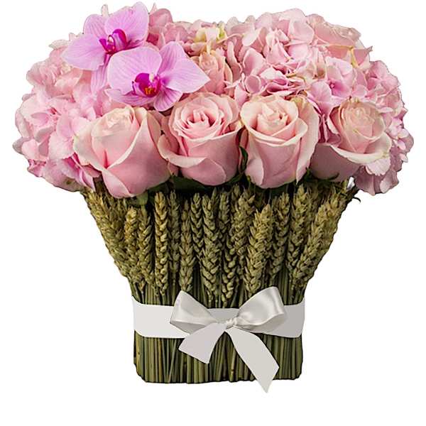 Pink roses and orchids arranged in a woven basket with a white ribbon