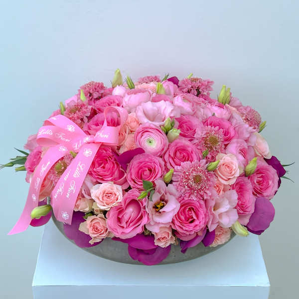 Pink rose bouquet in a low round vase with a pink ribbon