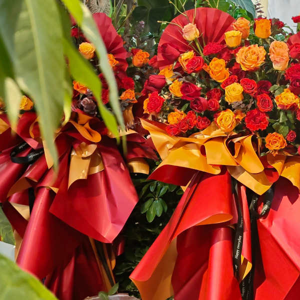 Large bouquet of red, orange, and yellow roses wrapped in red and gold paper