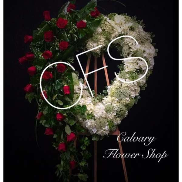 Heart-shaped floral wreath with red roses and white flowers on an easel