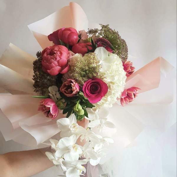 Hand-tied bouquet of pink and white flowers with trailing white orchids