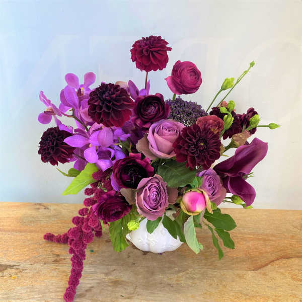 Purple and pink floral arrangement in a white vase