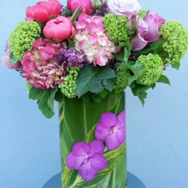 Pink and lavender flowers arranged in a tall glass vase