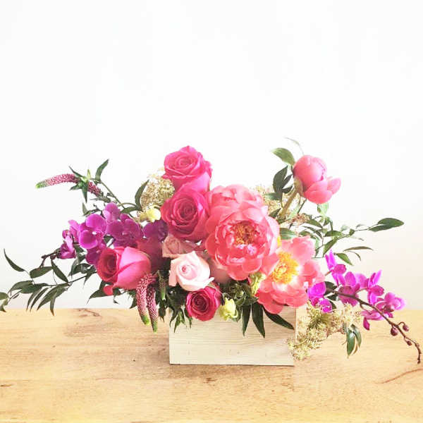 Pink and purple floral arrangement in a white box