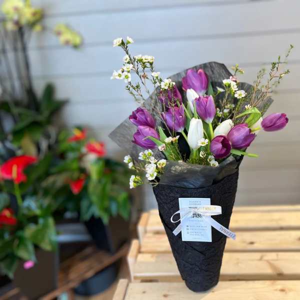 Purple and white tulips in black wrap with small white blossoms