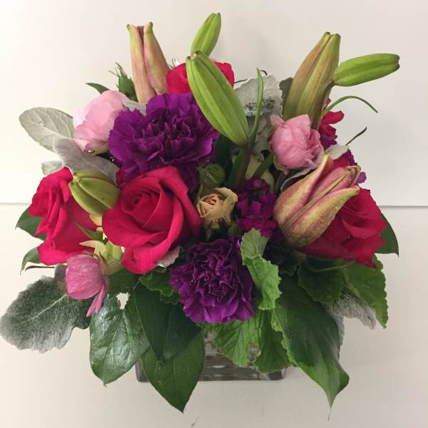Bouquet of pink and purple flowers with red roses in a glass vase
