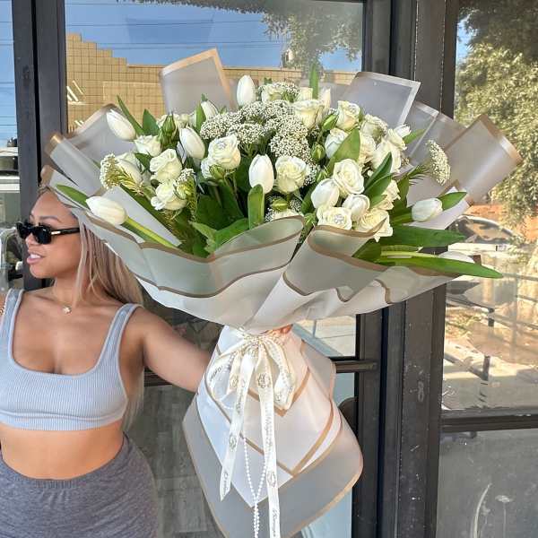 Large bouquet of white roses and tulips wrapped in sheer paper