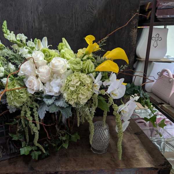 Large floral arrangement with white roses, green hydrangeas, and yellow calla lilies