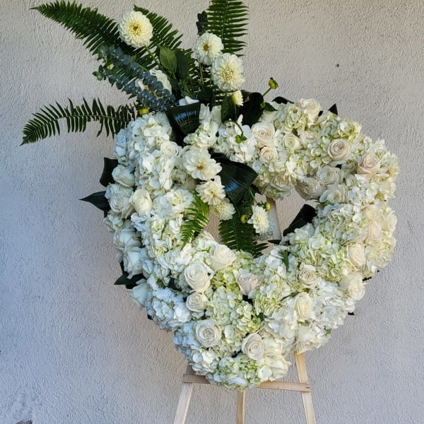 Large white floral wreath with roses and hydrangeas on an easel