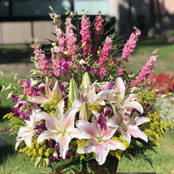 Basket arrangement of pink lilies, purple orchids, and yellow filler flowers