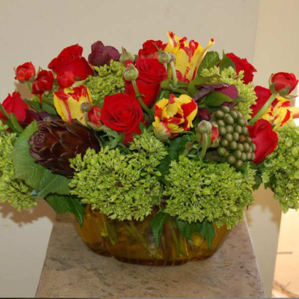 Mixed bouquet of red roses and yellow-red tulips in a glass bowl vase