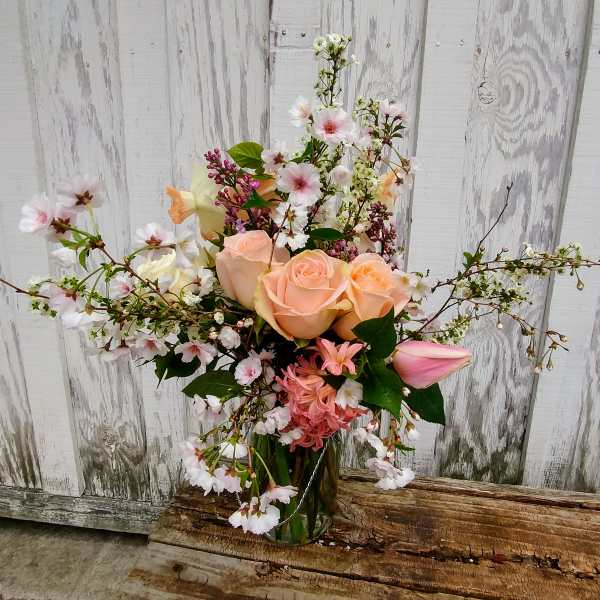 Peach roses and pink blossoms in a glass vase
