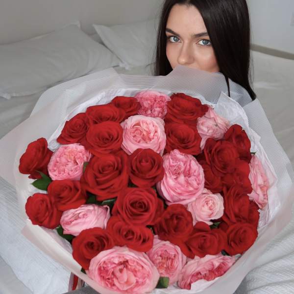 Woman holding a large bouquet of red and pink roses