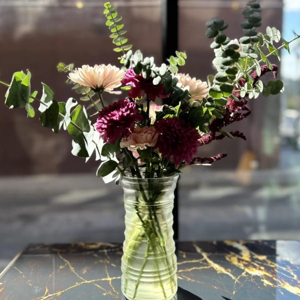 Mixed bouquet of pink and cream flowers in a clear glass vase