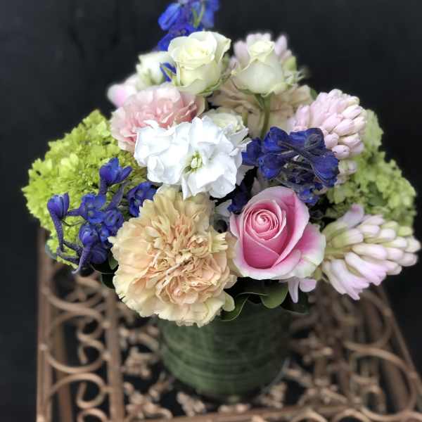 Mixed bouquet of pink, white, and blue flowers in a green vase