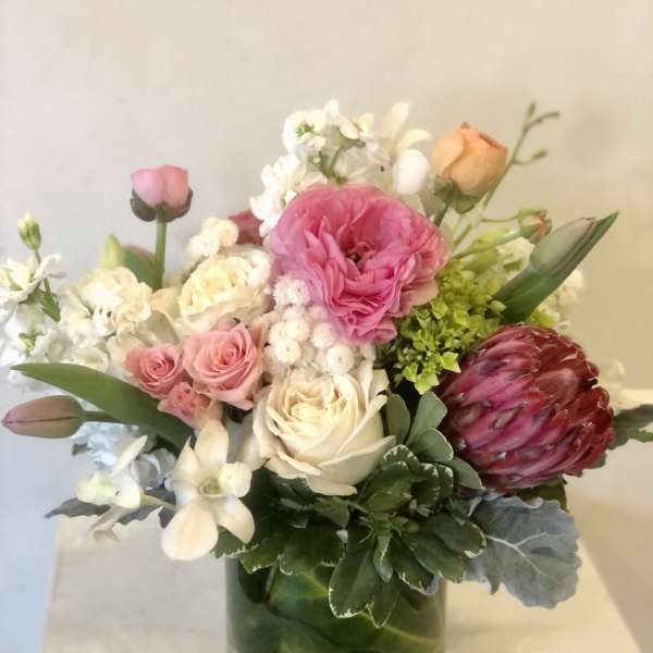 Mixed bouquet of pink, white, and peach flowers in a glass vase