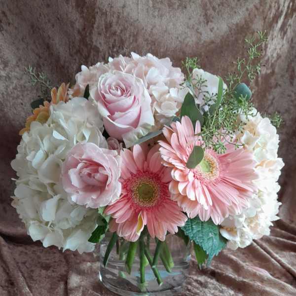 Pink roses and gerbera daisies in a clear glass vase