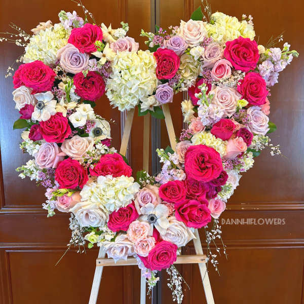 Heart-shaped floral arrangement of pink and cream roses on an easel