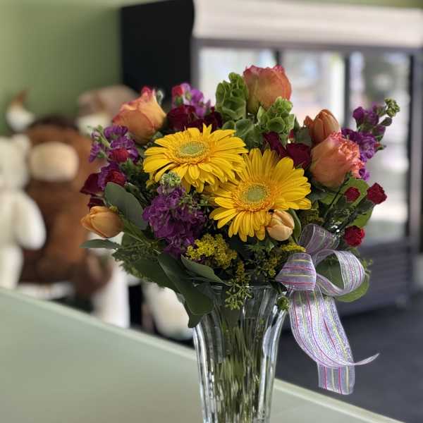 Bouquet of yellow gerbera daisies and mixed roses in a glass vase
