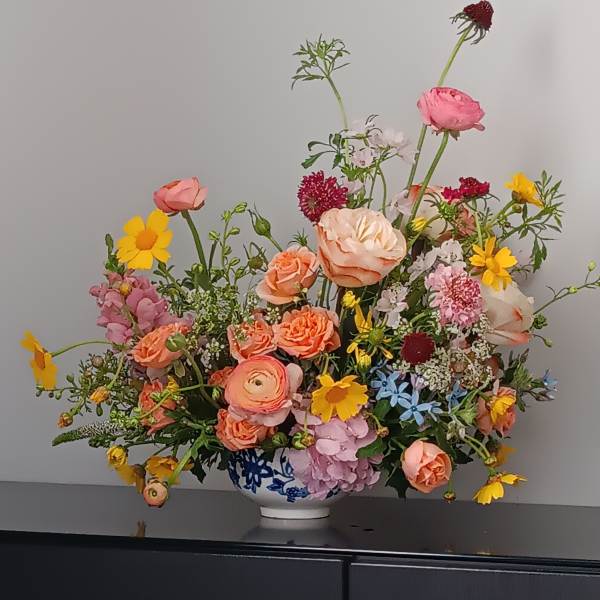 Mixed bouquet in a blue-and-white vase with pink, peach, and yellow flowers