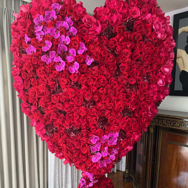 Large heart-shaped arrangement of red roses with pink orchids