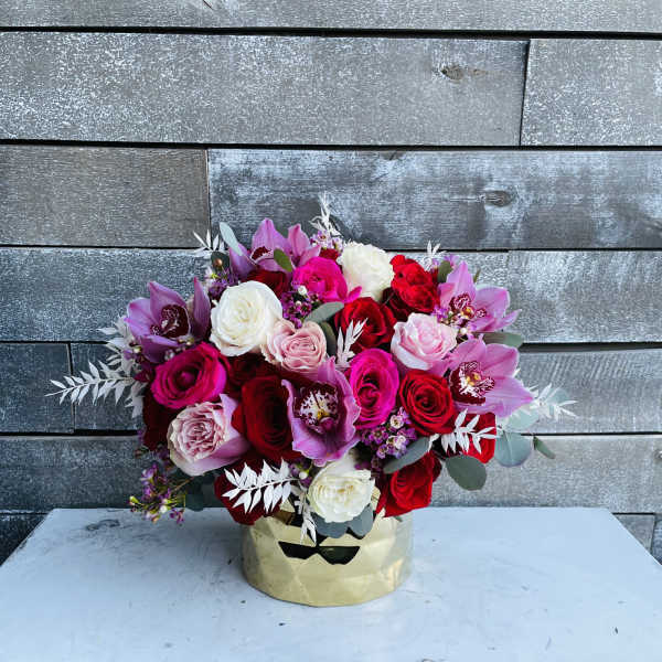 Bouquet of red, pink, white, and purple flowers in a gold container