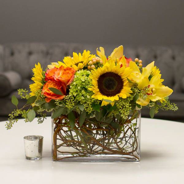 Sunflower and orange rose arrangement in a clear rectangular vase