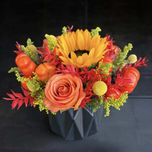 Orange rose and sunflower arrangement in a black vase