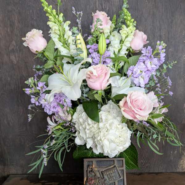 Bouquet of pink roses, white lilies, and lavender flowers in a vase