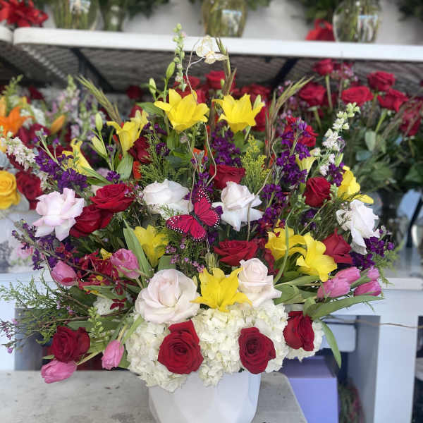 Mixed bouquet of roses, lilies, and hydrangeas in a white vase