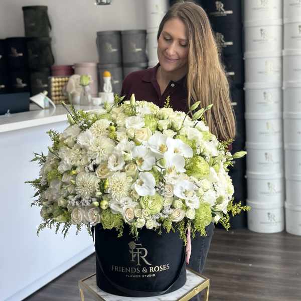 Large white floral arrangement in a black hat box