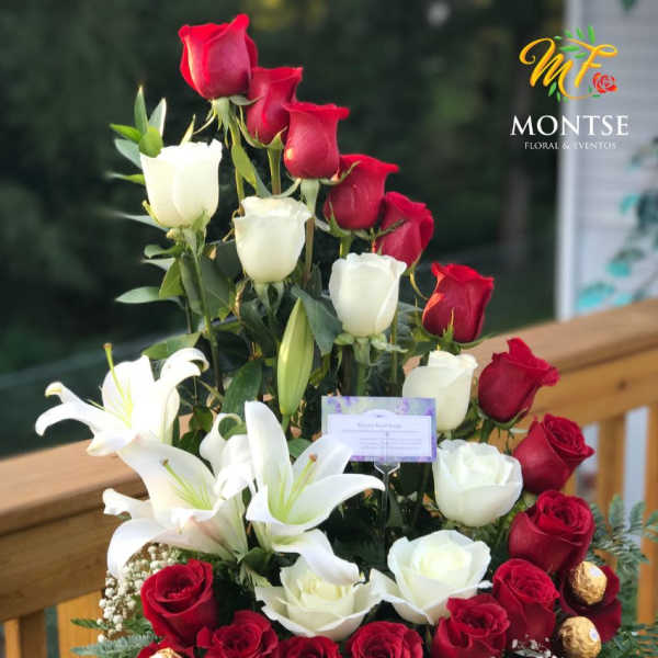 Basket arrangement of red and white roses with white lilies and gold chocolates