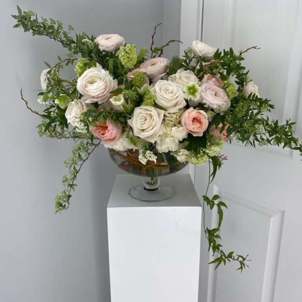 Pastel rose arrangement in a glass compote vase