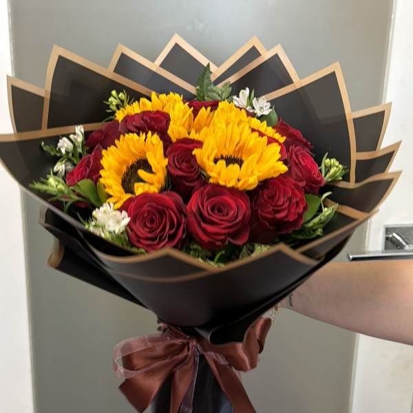 Bouquet of red roses and yellow sunflowers wrapped in black paper