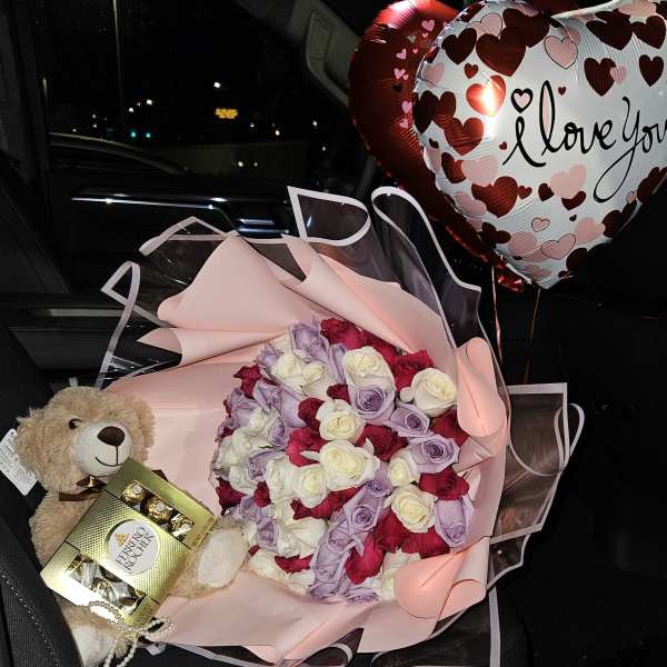 Bouquet of pink, white, red, and lavender roses with heart balloons and a teddy bear