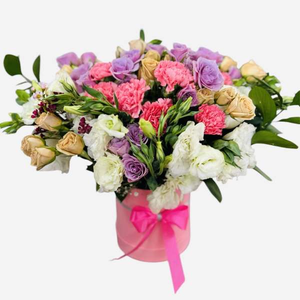 Bouquet of pink, purple, and cream flowers in a pink box with ribbon