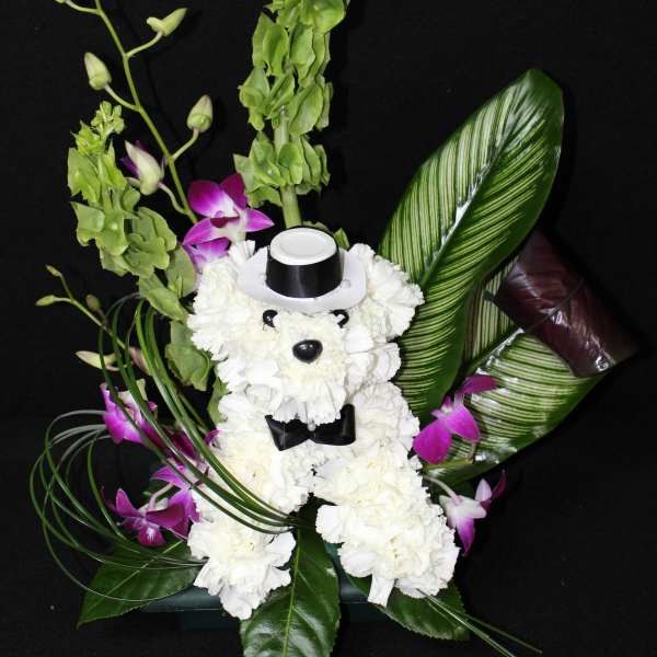 White teddy bear floral arrangement with purple orchids and green leaves