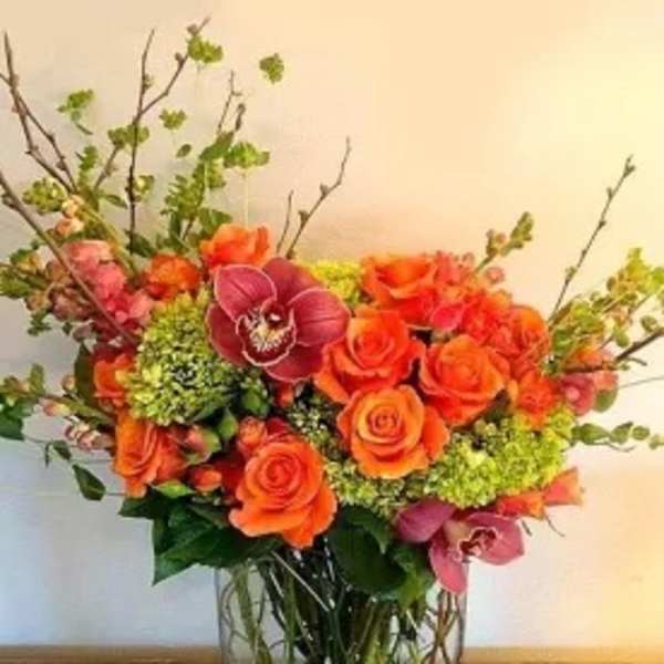 Orange roses and pink orchids in a glass vase