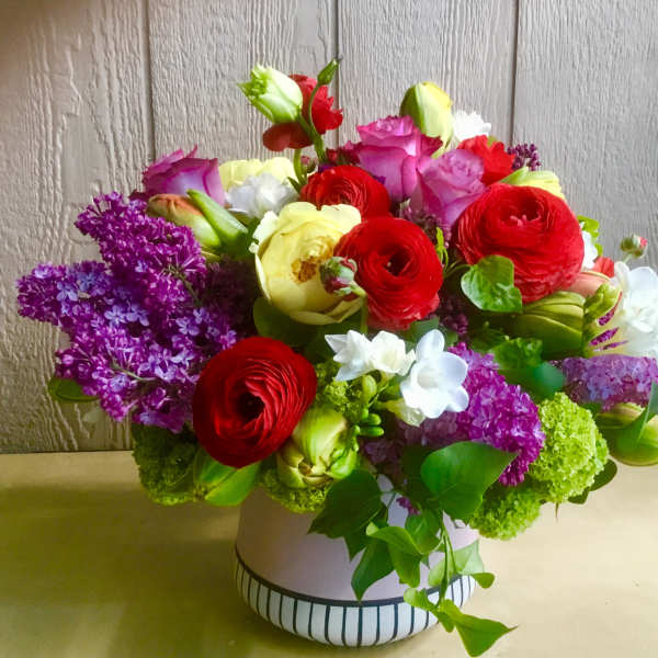Colorful mixed bouquet in a white vase with red, pink, purple, white, and green blooms
