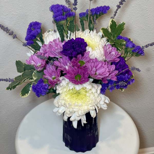 Purple and white chrysanthemum bouquet in a dark vase