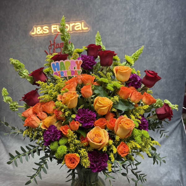 Large mixed bouquet of roses, carnations, and greenery in a glass vase