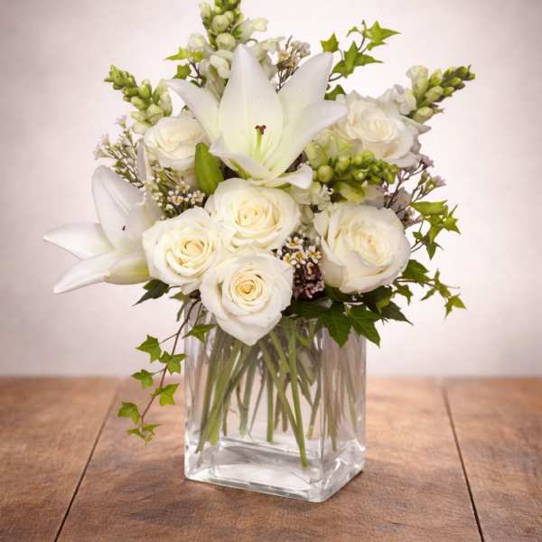 White roses and lilies arranged in a clear glass vase