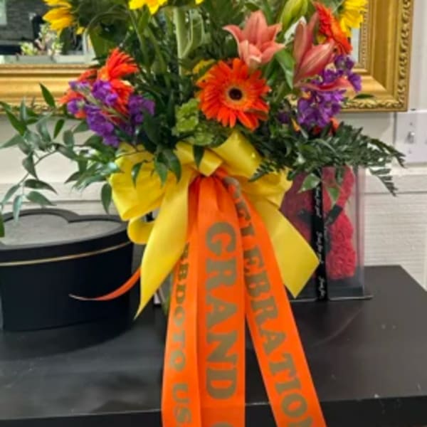 Tall floral arrangement with sunflowers, lilies, and gerbera daisies