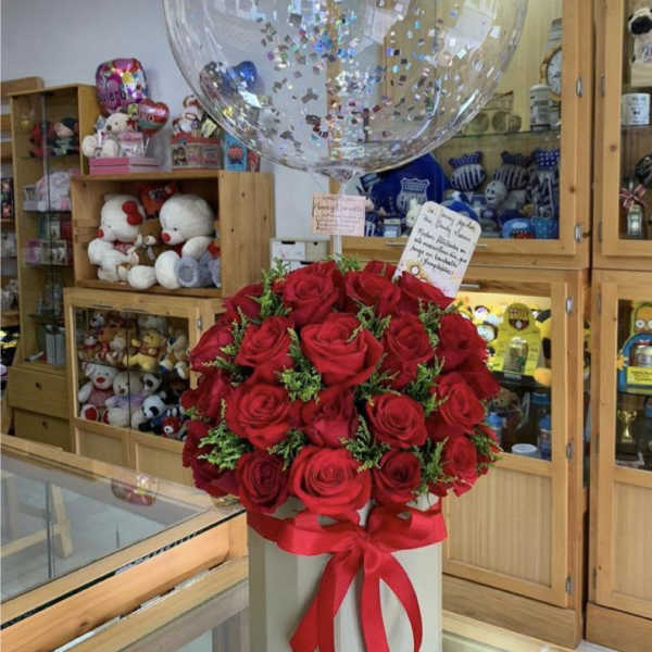 Red rose bouquet in a white box with a clear balloon above it