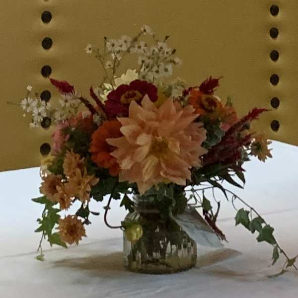 Mixed floral arrangement in a glass vase with peach, red, and orange blooms