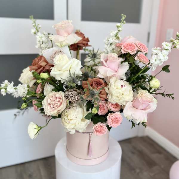 Pink and white roses arranged in a round hatbox