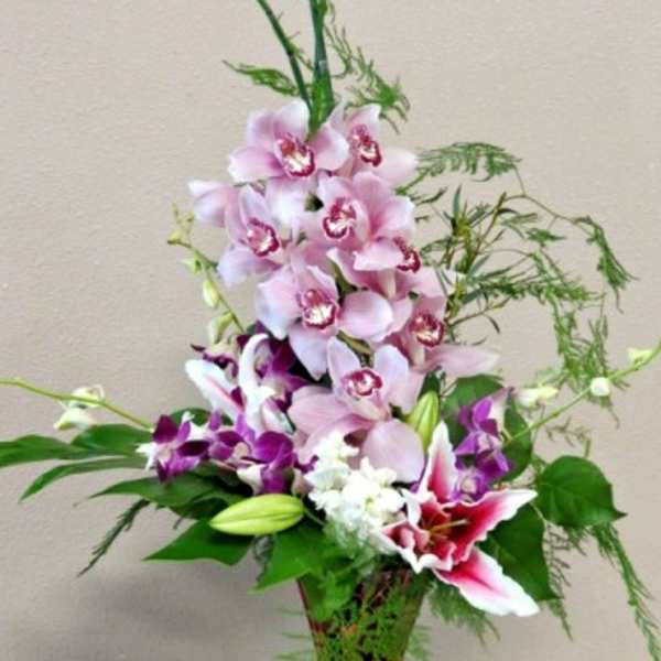 Tall bouquet of pink and purple orchids in a glass vase