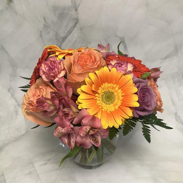 Mixed bouquet of roses, gerbera daisies, and alstroemeria in a glass vase