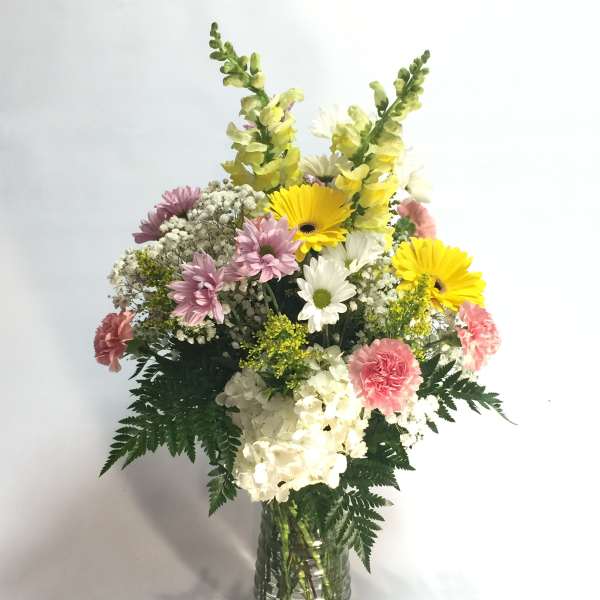 Mixed bouquet of yellow, pink, and white flowers in a glass vase
