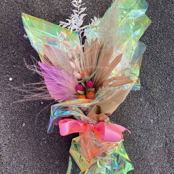 Bouquet with pink and orange dried flowers wrapped in iridescent paper